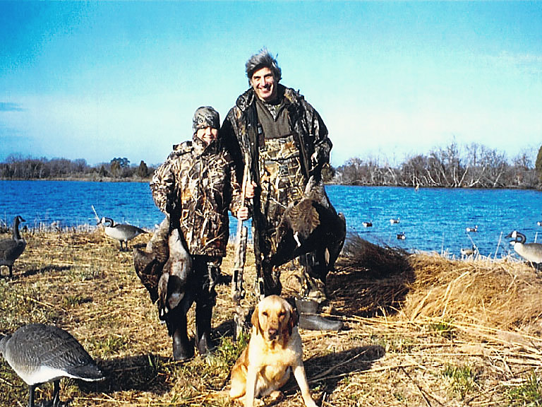 A yellow Lab, two hunters and the decoys at the water’s edge
