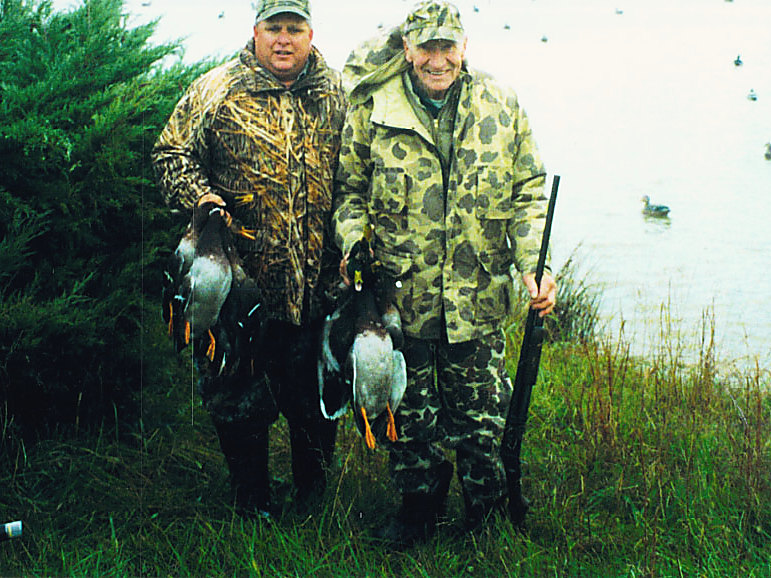 Two hunters with mallards by the pond