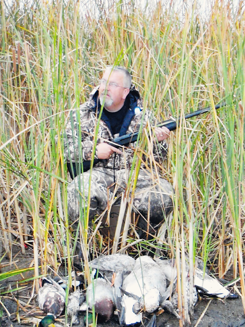 In the reeds, ducks at his feet